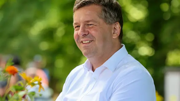 Porträt Sven Schulze in weißem Hemd mit Blumen im Hintergrund | picture alliance/dpa | Peter Gercke Porträt Sven Schulze in weißem Hemd mit Blumen im Hintergrund