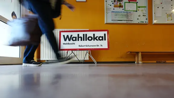 Eine Person ist in einem Wahllokal unterwegs, | picture alliance/dpa | Kay Nietfeld Eine Person ist in einem Wahllokal unterwegs,